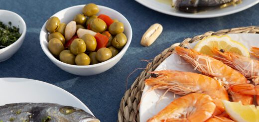 Shrimp platter with lemon wedges, olives, and other seafood dishes on a blue table.
